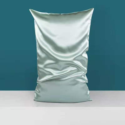 A large, shiny satin pillowcase in light green, from the Aloha Relax collection, sits upright on a white surface against a teal background. This luxurious Double-sided Silk Silk Heavy Sleep Pillowcase is crafted from mulberry silk fabric, with a slightly reflective surface and visible folds and creases that exude an air of elegance and sophistication.