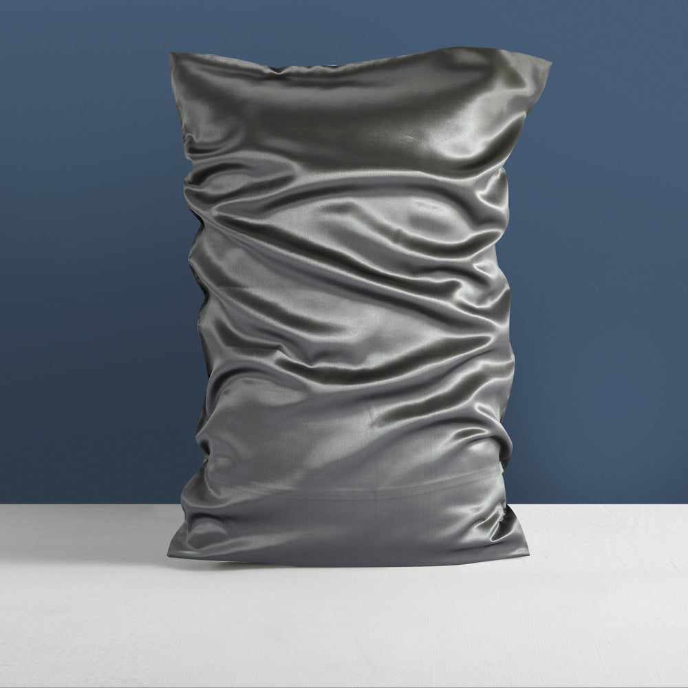 A gleaming, wrinkled, silver pillowcase from Aloha Relax's Double-sided Silk Silk Heavy Sleep Pillowcase collection stands upright against a blue wall on a light gray surface, embodying palace luxury with its smooth and reflective mulberry silk texture.