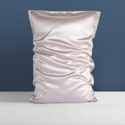 An elegant Double-sided Silk Silk Heavy Sleep Pillowcase by Aloha Relax is showcased upright against a deep blue backdrop. The light-colored mulberry silk fabric, smooth and adorned with natural folds, rests gracefully on a soft gray surface, emanating the luxurious essence of palace bedding.