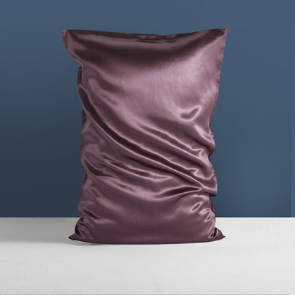 The Double-sided Silk Heavy Sleep Pillowcase by Aloha Relax, made from glossy mulberry silk, is showcased crumpled on a flat white surface against a muted blue background.