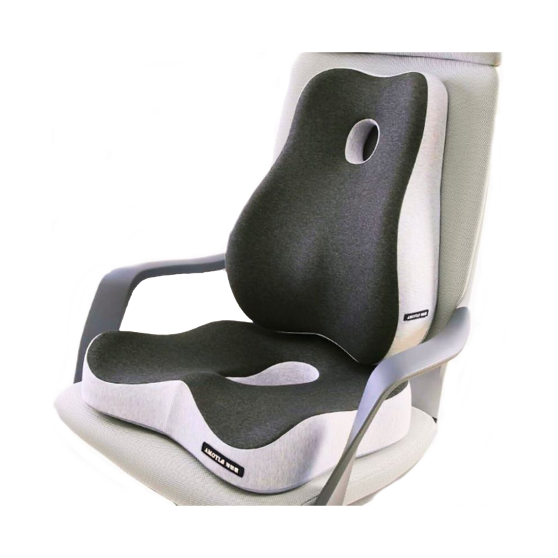 The image shows the Aloha Relax Wellness Bundle, featuring a contoured memory foam seat cushion and backrest on a chair. The cushion, in a grey and white color scheme, includes an ergonomic cutout in the middle for added support. Designed to enhance comfort while sitting, it promotes stress relief and ensures an Aloha Relax experience.