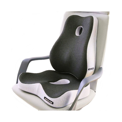 The image shows the Aloha Relax Wellness Bundle, featuring a contoured memory foam seat cushion and backrest on a chair. The cushion, in a grey and white color scheme, includes an ergonomic cutout in the middle for added support. Designed to enhance comfort while sitting, it promotes stress relief and ensures an Aloha Relax experience.