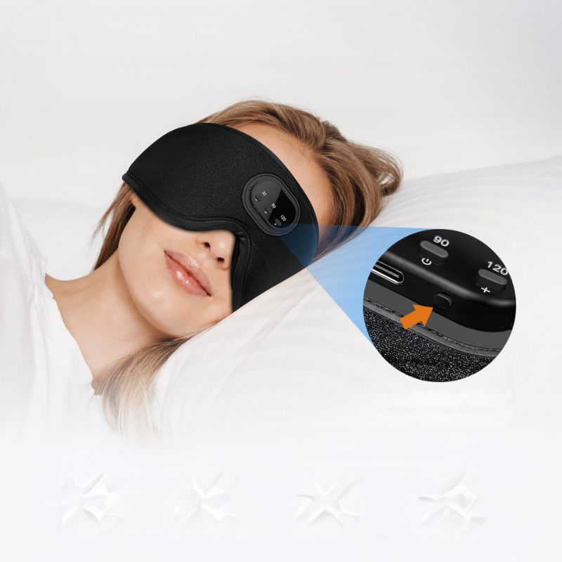 A woman is lying down with the 3D Bluetooth Sleep Mask With Breathable Intelligence by Aloha Relax covering her eyes. The mask, shown in a close-up circular insert, features buttons likely controlling its various functions. She appears to be enjoying a restful sleep, resting on a white pillow and wearing a white top.